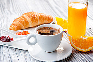 Kaffe, et glass med juice samt croissant.